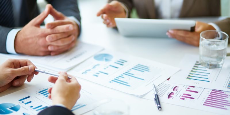 Image of business documents, pen and glasses on workplace during meeting of partners